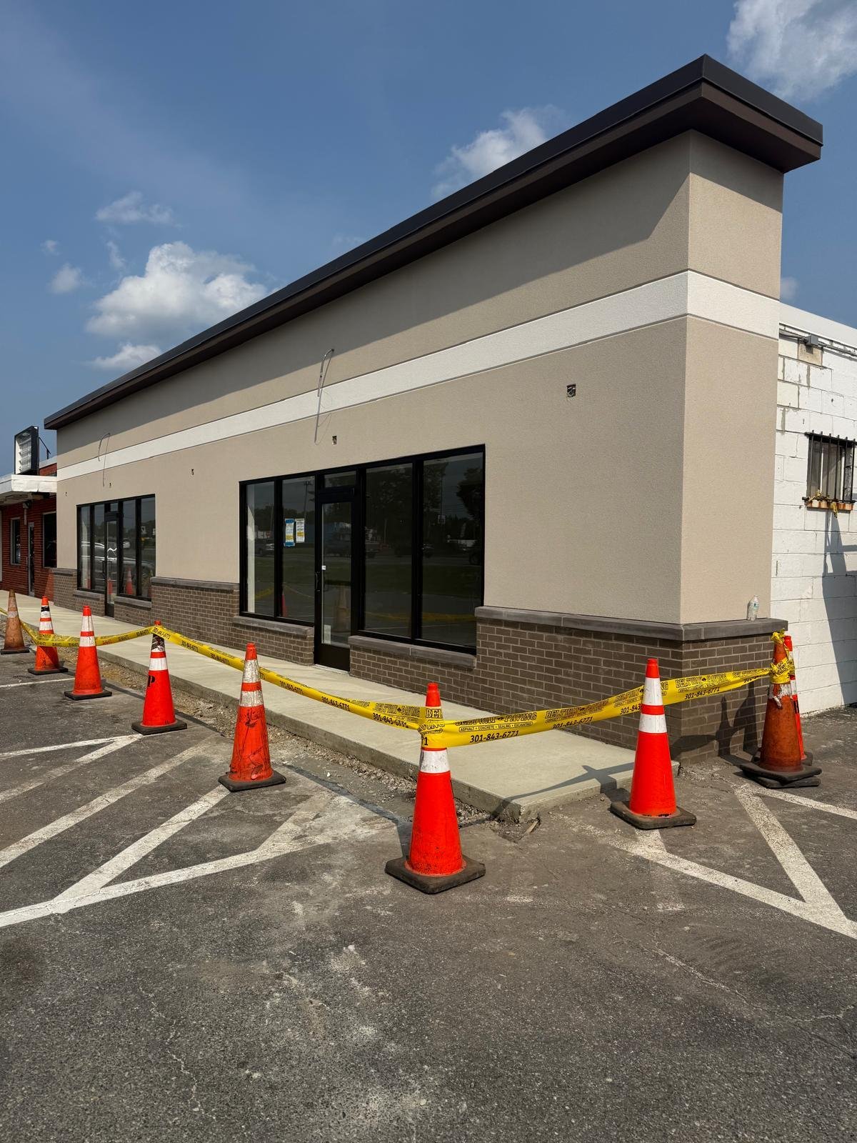 Close exterior view of a commercial renovation with finished stucco facade, brick base and storefront glazing